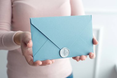 Close-up davetiye kartı zarf ellerini, önden görünüm tutan kadın