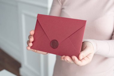 Close-up davetiye kartı zarf ellerini, önden görünüm tutan kadın