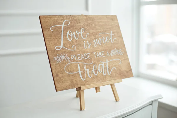 The close-up photo of the wooden plaque with the signs Love to the wedding standing on white background