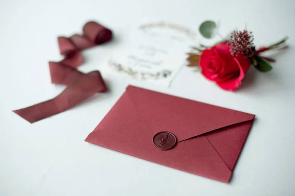 Wedding invitation as a decorated letter on a white tablecloth with a flower arrangement