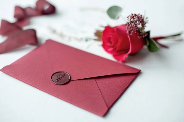 Wedding invitation as a decorated letter on a white tablecloth with a flower arrangement