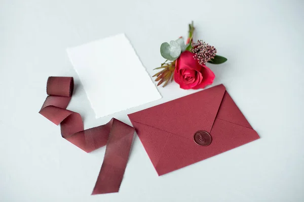 Wedding invitation as a decorated letter on a white tablecloth with a flower arrangement