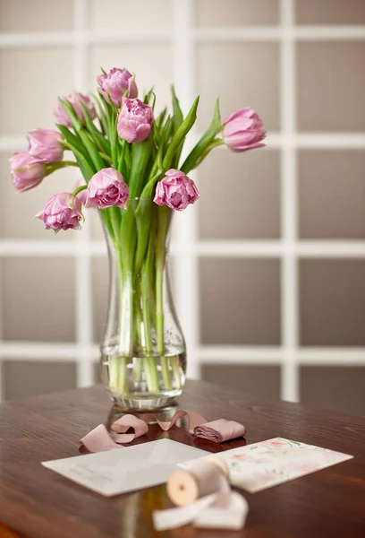 Flores de color púrpura lavanda en un jarrón dorado sobre una mesa de madera en un elegante interior con tarjetas de felicitación y una caja de terciopelo con decoración . —  Fotos de Stock