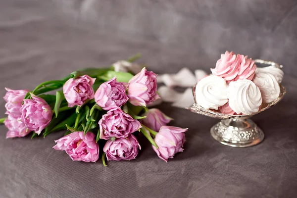 Tulipanes de color púrpura lavanda junto a un jarrón de metal vintage lleno de malvavisco casero en un elegante interior, concepto de felicitación . —  Fotos de Stock