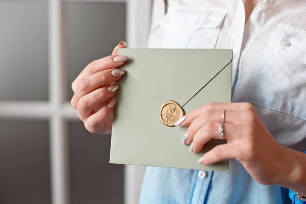 Närbild kvinna med smal kropp håller i händer det kort grå-grön färg fyrkantig form kuvert inbjudningskort. — Stockfoto