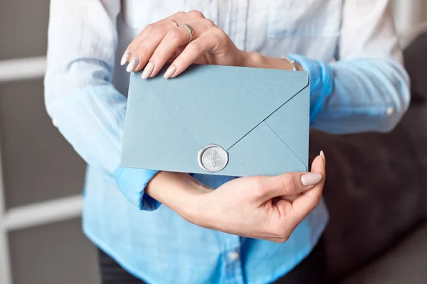 Primer plano de una joven sosteniendo un sobre de regalo rectangular azul con invitaciones, productos y servicios tarjeta . —  Fotos de Stock