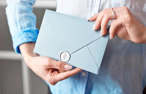 特写镜头, 一个年轻女孩拿着一个蓝色长方形的礼物信封, 并附有请柬、商品和服务卡. — 图库照片