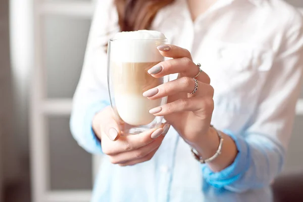 Close-up of female hands in office clothes holding a glass cup of coffee with soy milk during a break at work, lifestyle concept. — Stock Photo, Image