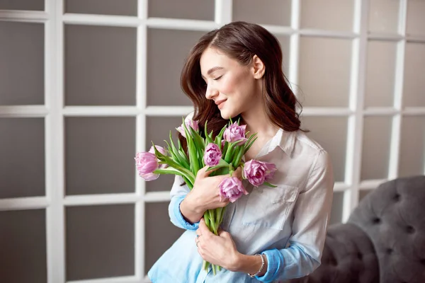 Молодая красивая брюнетка с весенним букетом тюльпанов в руках. Стиль жизни . — стоковое фото