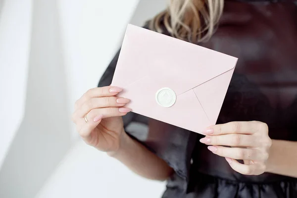 Foto de close-up de mãos femininas segurando um envelope de convite de prata com um selo de cera, um certificado de presente, um cartão postal, um cartão de convite de casamento . — Fotografia de Stock