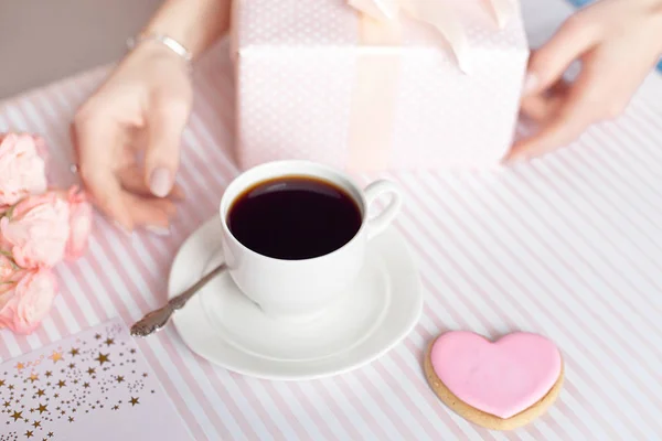 Mother's day concept - a gift for women hands with a white cup of coffee and roses. Copy space.