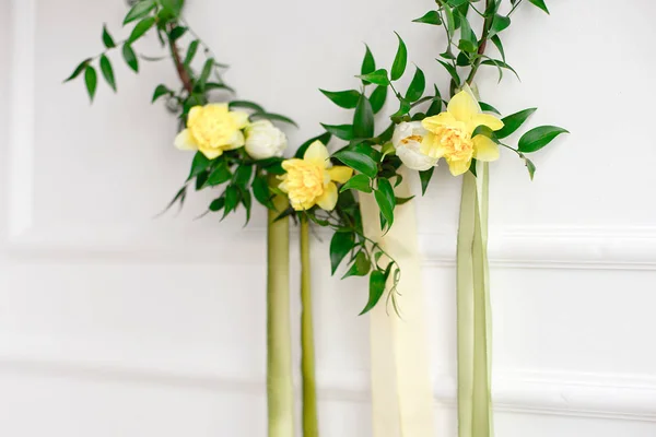 Close-up green wreath of narcissus and plants on the white wall