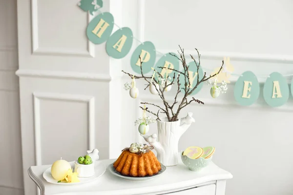 Décoration de la table de Pâques, un vase avec une branche et des décorations de fleurs et d'œufs, biscuits au lapin, gâteau de Pâques et bonbons . — Photo