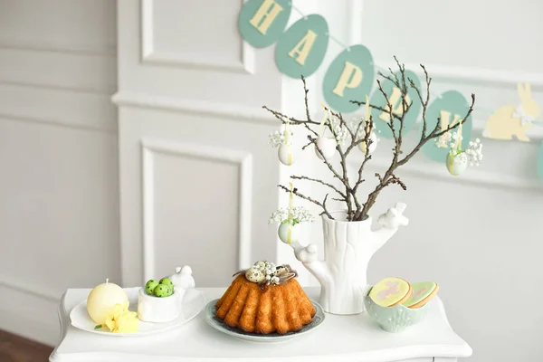 Decoração da mesa de Páscoa, um vaso com um ramo e decorações de flores e ovos, biscoitos com coelho, bolo de Páscoa e doces . — Fotografia de Stock
