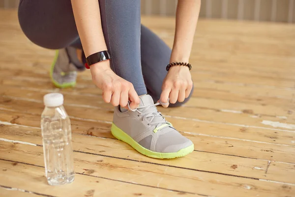 Kadının elleri üzerinde spor salonunda spor ayakkabı ayakkabı bağcığı bağlama yakın çekim önden görünümü