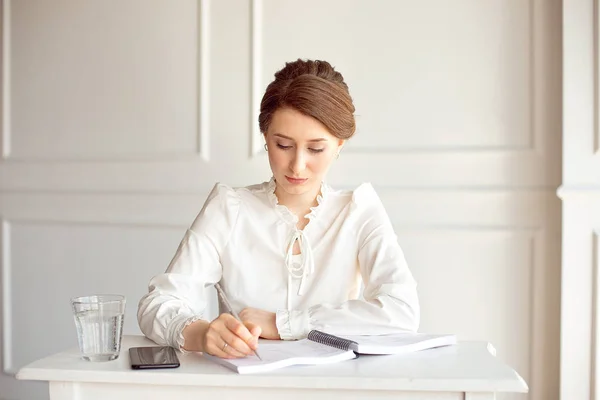 Jonge vrouw ondertekent belangrijke documenten zittend aan haar Bureau in een kantoor. Pretty Kaukasische vrouwelijke werken in een kantoor aan huis — Stockfoto