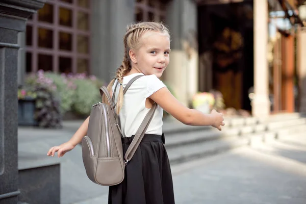 Ragazza sorridente felice sta andando a scuola per la prima volta con borsa andare a scuola elementare. Alunno andare a studiare con lo zaino — Foto Stock