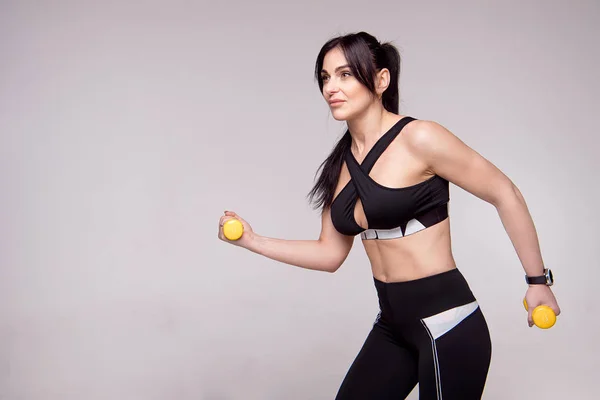 Портрет спортивний молодий Європейський фітнес жінка роблять тренування з гантелями ізольовані на сірий фон. — стокове фото