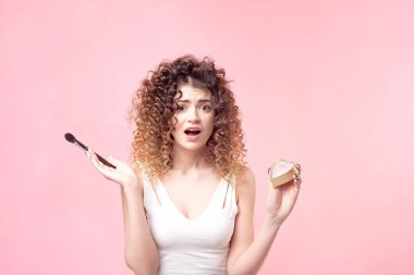 Makyaj fırçasıyla fondöten tozu süren güzel bir genç kadın.