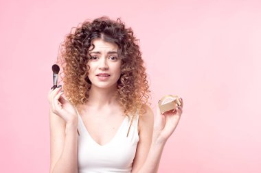 Makyaj fırçasıyla fondöten tozu süren güzel bir genç kadın.