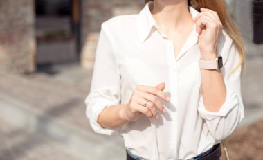 Beyaz gömlek ve güneş gözlüğü ile başarılı bir mutlu iş kadını Portresi. Akıllı saat iş merkezinin girişinde duruyor