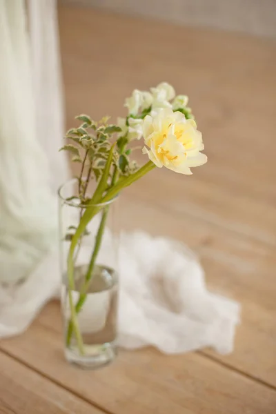 ガラスの花瓶の白いワックスキャンドルに咲く白いピオニーチューリップマッティオラの枝は、屋内の木製の光の床に立っています. — ストック写真