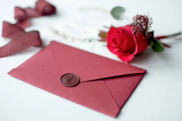 Invitation de mariage comme une lettre décorée sur une nappe blanche avec un arrangement de fleurs . — Photo