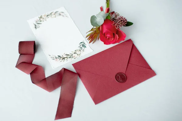 Invitation de mariage comme une lettre décorée sur une nappe blanche avec un arrangement de fleurs . — Photo