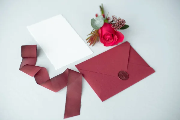 Invitation de mariage comme une lettre décorée sur une nappe blanche avec un arrangement de fleurs . — Photo