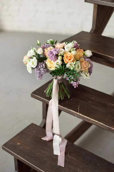 Beau bouquet de fleurs de roses et de lilas sur une échelle en bois contre un mur de briques blanches . — Photo