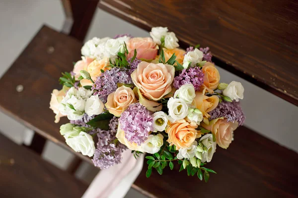 Wedding bouquet of pink roses with a lilac on a blurred background on a wooden staircase. — Stock Photo, Image