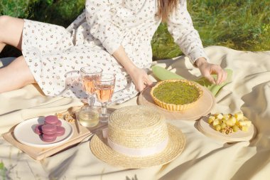 Bahçemacaroon fırını şeffaf bardak bahçede bej kumaş üzerinde kırmızı bez üzerinde meyve ve fırın ile piknik sepeti