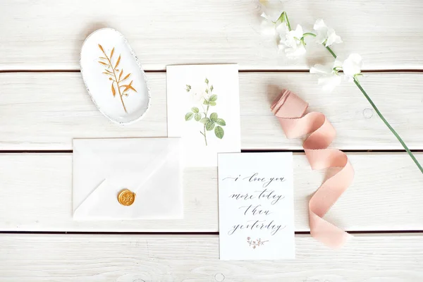 Bröllop inbjudan som inredda brev på en vit duk med blomsterarrangemang. — Stockfoto