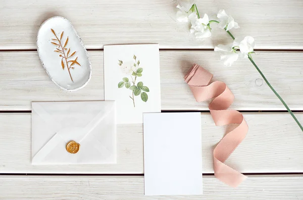 Bröllop inbjudan som inredda brev på en vit duk med blomsterarrangemang. — Stockfoto