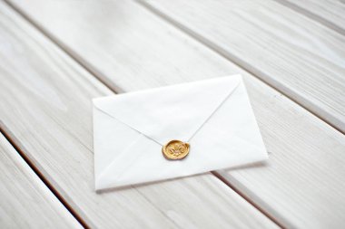 Beyaz bir masa örtüsü üzerinde süslü bir mektup olarak düğün davetiyesi.