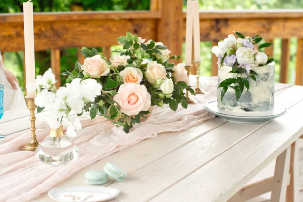 Свадебный стол в саду, цветочные композиции, свечи в стиле винтаж на открытом воздухе. Свадебный торт с цветами Украшенный стол с цветами, обслуживается для двух человек — стоковое фото