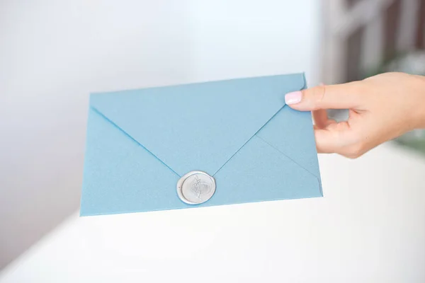 Zbliżenie kobieta z szczupły ciało trzymanie w ręce karta koperta kolor kształt kwadrat niebieski zaproszenie. — Zdjęcie stockowe