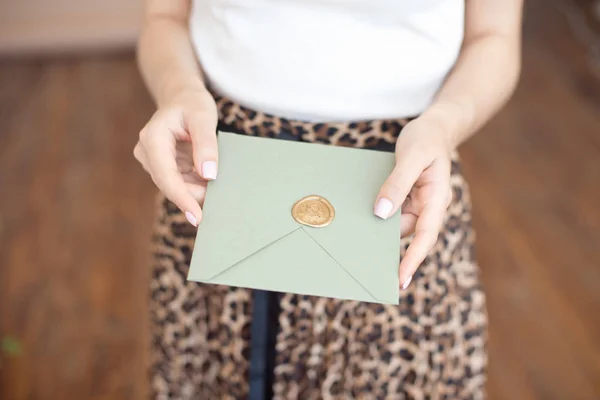 Foto de close-up de mãos femininas segurando um envelope de convite azul ou rosa prateado com um selo de cera, um certificado de presente, um cartão postal, um cartão de convite de casamento . — Fotografia de Stock