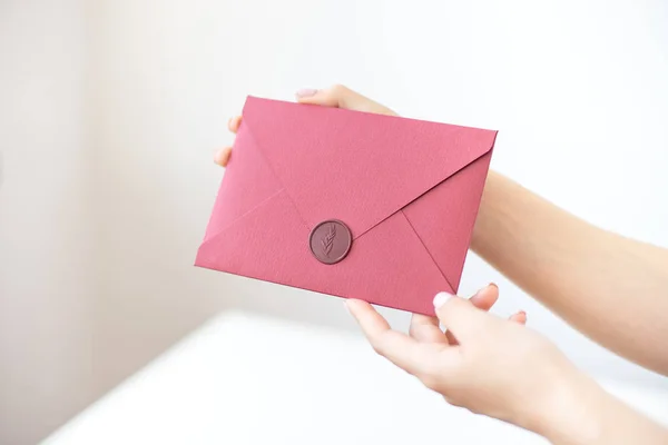 Nahaufnahme von weiblichen Händen mit einem silbernen Einladungsumschlag mit Wachssiegel, einem Gutschein, einer Postkarte, einer Hochzeitseinladungskarte. — Stockfoto