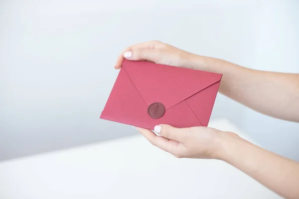 Närbild foto av kvinnliga händer som håller en silver inbjudan kuvertet med ett vax tätning, ett presentkort, ett vykort, en bröllop inbjudningskort. — Stockfoto