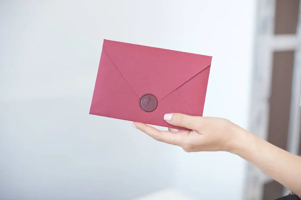 Foto de close-up de mãos femininas segurando um envelope de convite de prata com um selo de cera, um certificado de presente, um cartão postal, um cartão de convite de casamento . — Fotografia de Stock