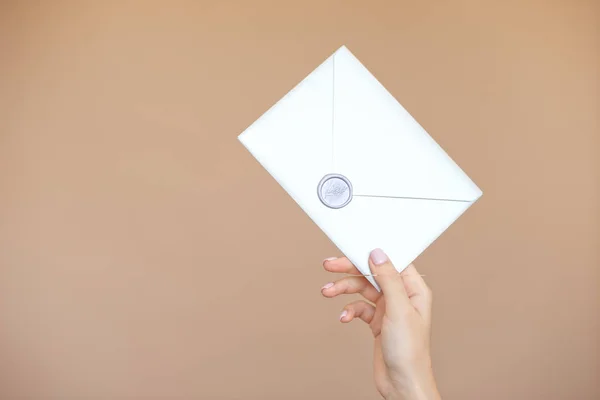 Close-up photo of female hands with wax seal with invitation envelope, gift certificate, postcard, wedding invitation card.