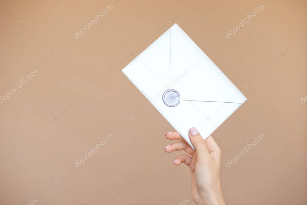 Close-up photo of female hands with wax seal with invitation envelope, gift certificate, postcard, wedding invitation card.