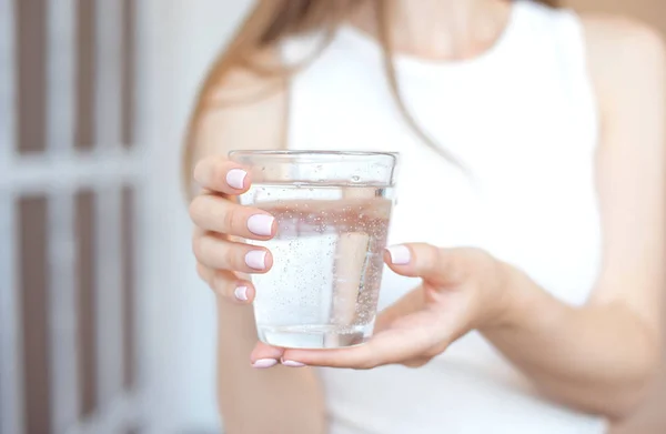 Manos femeninas sosteniendo un vaso de agua transparente. Un vaso de agua mineral limpia en las manos, bebida saludable . —  Fotos de Stock