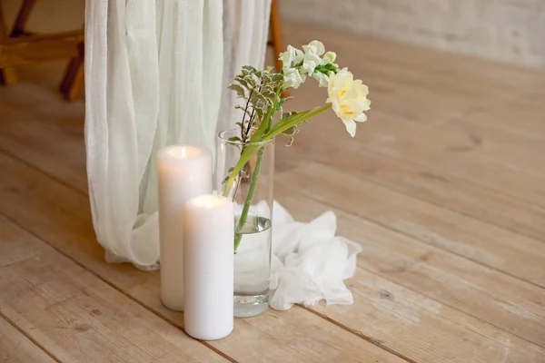 Branch of blooming white peony tulip Mattiola branch in a glass vase white wax candles stand on the wooden light floor indoors. — Stock Photo, Image