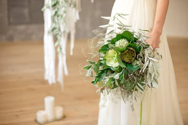 Bouquet da sposa fresco e arioso leggermente spettinato con palla grinn, brunia, eringum, eustoma, asparagi ed eucalipto nelle mani della sposa in un abito da sposa in stile boho bianco . — Foto Stock