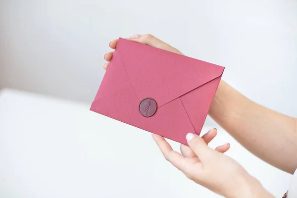 Foto de close-up de mãos femininas segurando um envelope de convite de prata com um selo de cera, um certificado de presente, um cartão postal, um cartão de convite de casamento . — Fotografia de Stock