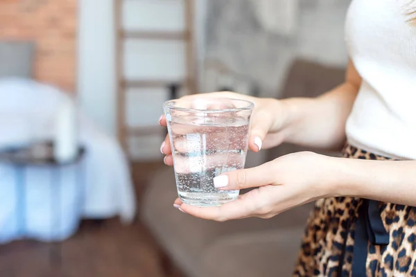 Girl in white top and skirt with a trendy print holds a glass of clean water to maintain the body's health and water balance. — Stock Photo, Image