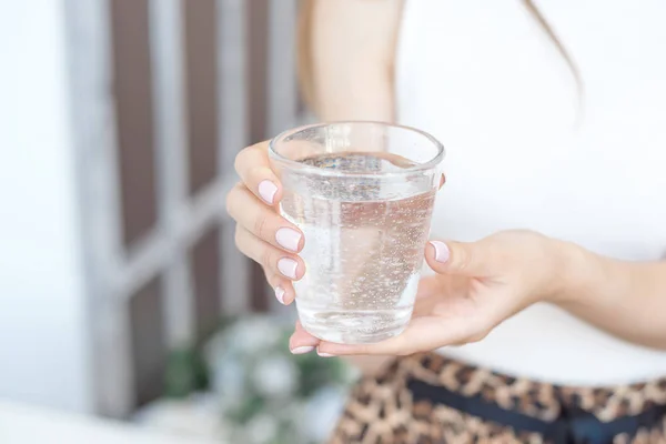 Close-up girl hands in the office stands in the sunlight holding a glass of clean water in between work — Stock Photo, Image