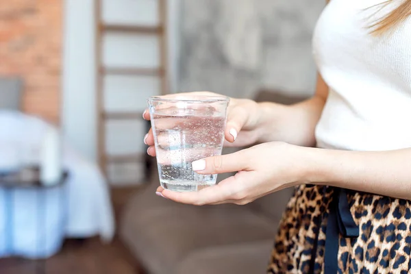 Chica en la parte superior blanca y falda con un estampado de moda sostiene un vaso de agua limpia para mantener el equilibrio de salud y agua del cuerpo . —  Fotos de Stock